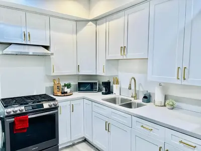 a white kitchen with white cabinets and a sink at Newly Built Stylish Modern 2B In LA in North Sherman Way