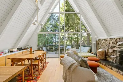 a living room with a table and a large window at Luxury A-Frame Retreat in Lake Arrowhead