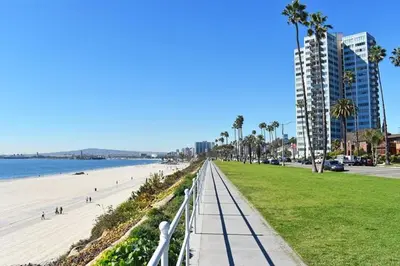 a walkway next to a beach with palm trees and a building at BonVoyage-Sleep&Sail Overnight Stays-Sleeps 6-8 in Long Beach