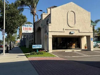 a building with a motel sign in front of a street at Fiesta Inn Los Angeles - Bell Gardens in Bell Gardens