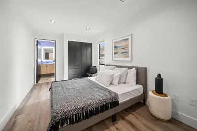 a bedroom with a bed with white walls and wooden floors at Tulum Style in Sherman Oaks in Garnsey