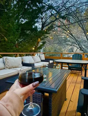 a person holding a glass of wine on a deck at Snow Valley Retreat With Spa in Running Springs