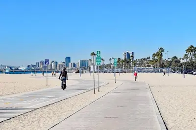 a person riding a bike on a sidewalk on the beach at Ocean View Suite by Convention Center & Beach in Long Beach