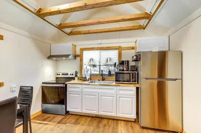 a kitchen with white cabinets and a stainless steel refrigerator at Tiny Home with Deck and Mtn Views in Lake Arrowhead! in Lake Arrowhead