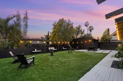 a backyard with a lawn with chairs and tables at Malibu Beach House by Stay Awhile Villas in Malibu
