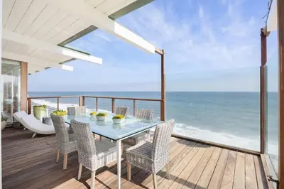 a dining table and chairs on a deck with the ocean at Malibu Cove Colony Beach by Stay Awhile Villas in Malibu