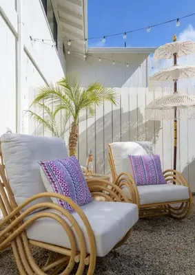 two wicker chairs sitting on a balcony with palm trees at Outdoor Spaces and Coastal Sanctuary in Summerland