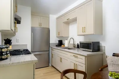 a kitchen with white cabinets and a stainless steel refrigerator at Outdoor Spaces and Coastal Sanctuary in Summerland