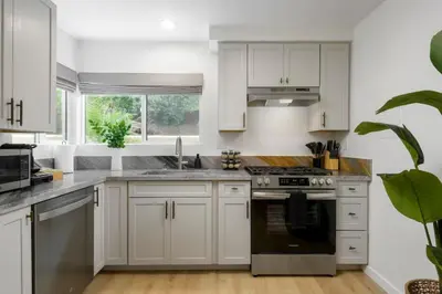 a kitchen with white cabinets and stainless steel appliances at Private Garden and Tranquil Haven in Summerland