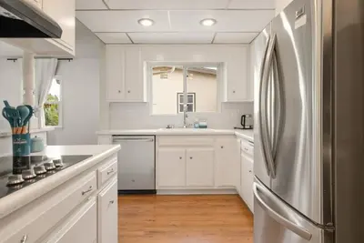 a kitchen with white cabinets and a stainless steel refrigerator at Vintage Vibes Near Airport Games Sleeps 8 in Long Beach