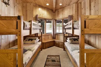 two bunk beds in a room with wooden walls at Bear Lake Lodge Lakefront Incredible Lake House Chalet in Big Bear Lake