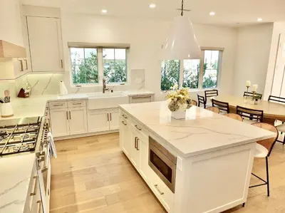a large kitchen with white cabinets and a dining room at Beach Paradise - Stunning 3-Story in Long Beach in Long Beach