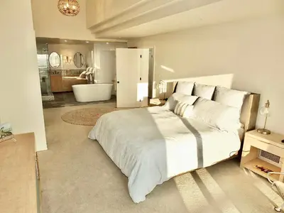 a bedroom with a large bed and a bathroom at Beachfront Estate - LB Peninsula in Long Beach