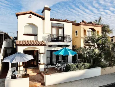 a large house with two umbrellas and a patio at Beauty by the Beach - SoCal Fun in Long Beach