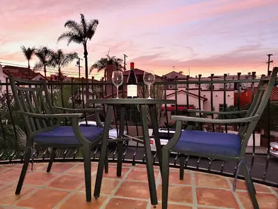 a table and two chairs with wine glasses on a balcony at Beauty by the Beach - SoCal Fun in Long Beach