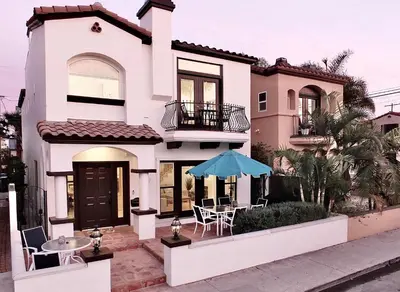 a white house with a table and a blue umbrella at Beauty by the Beach - SoCal Fun in Long Beach