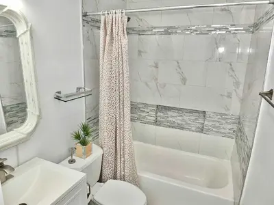 a white bathroom with a shower curtain and a toilet at Bellflower Breeze - Charming 3 BDR in Long Beach in Long Beach