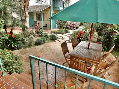 a wooden table and chairs with a green umbrella at Belmont Heights Retreat - Stunning Gardens in Long Beach