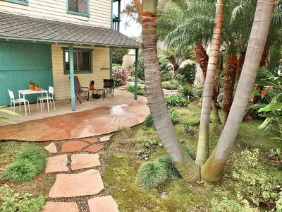 a patio with two palm trees and a house at Belmont Heights Retreat - Stunning Gardens in Long Beach