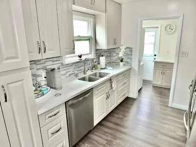 a kitchen with white cabinets and a sink at Greenbelt Guesthouse - Unlimited Peace & Privacy Golf Bowling Green & More in Long Beach