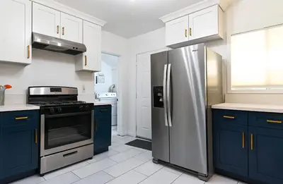 a kitchen with blue cabinets and a stainless steel refrigerator at Immaculate 3BDR Bungalow - 5-Min Walk to Beach in Long Beach