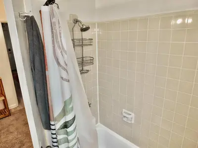 a shower with a striped shower curtain in a bathroom at Sand Sun & Second - Charming Studio within Walking Distance to Beach in Long Beach