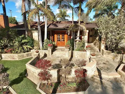 a house with palm trees and a house with a garden at The Belmont Beach Bungalow - Pool & Hot tub in Long Beach