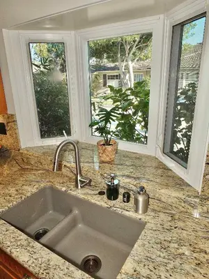 a kitchen counter with a sink and two windows at The Belmont Beach Bungalow - Pool & Hot tub in Long Beach
