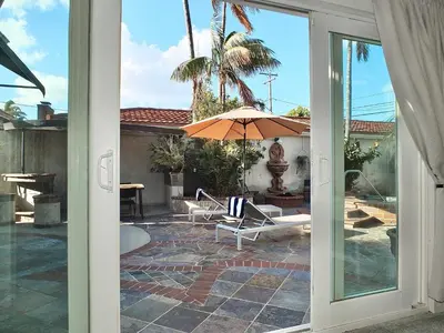 an open door to a patio with an umbrella at The Belmont Beach Bungalow - Pool & Hot tub in Long Beach