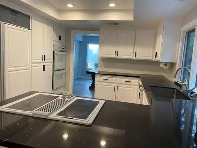 a kitchen with white cabinets and a black counter top at 5 Bedroom House with fabulous mountain views in Hacienda Heights