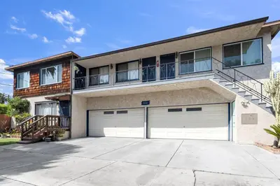 a house with two garage doors and a balcony at Beautifully Remodeled 2bed1bath Apartment Top Location 15 min to Beach in Los Angeles