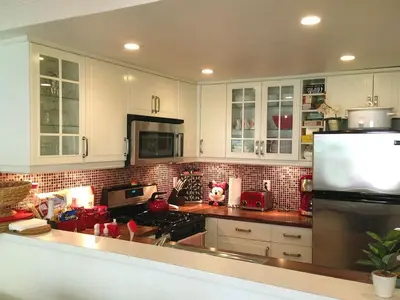 a kitchen with white cabinets and a refrigerator at Pixie Hollow by Funtierland Vacation Rentals in Anaheim