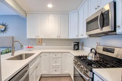 a kitchen with white cabinets and a stove top oven at Maleficents Retreat by Funtierland Vacation Rentals in Anaheim