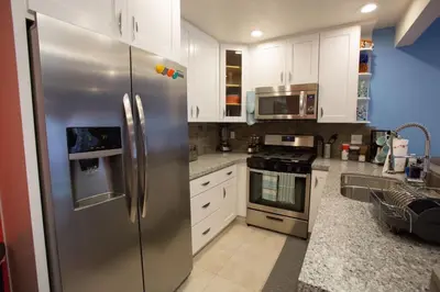 a kitchen with a stainless steel refrigerator and white cabinets at Under the Sea by Funtierland Vacation Rentals in Anaheim