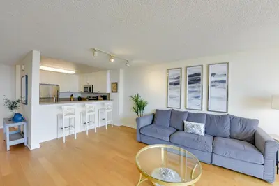 a living room with a blue couch and a kitchen at Oceanfront Bliss, Beach & Marina Views, Roomy 1BR in Los Angeles
