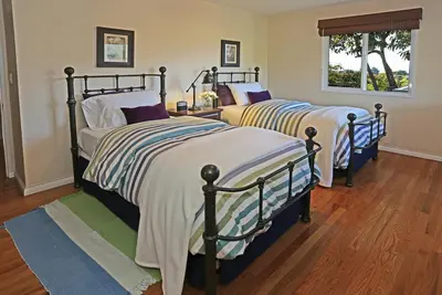 two beds sitting in a room with wood floors at Bella Vista by Paradise Retreats in Carpinteria