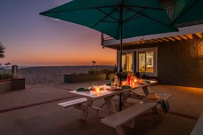 a picnic table with an umbrella on the beach at Carpinteria Dreamin by Paradise Retreats in Carpinteria