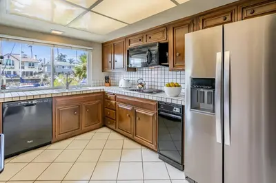a kitchen with wooden cabinets and stainless steel appliances at Keys Retreat by Paradise Retreats in Ventura