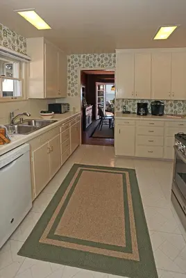 a large kitchen with white cabinets and a sink at Rincon Retreat by Paradise Retreats in Carpinteria