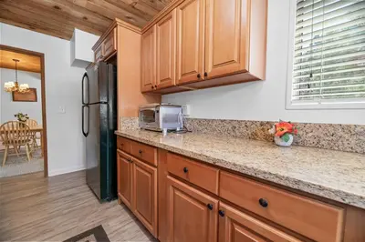 a kitchen with wooden cabinets and a refrigerator at Modern Lake Cabin for Family, Friends and Pets! in Big Bear Lake