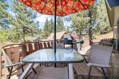 a table and chairs on a balcony with an umbrella at Modern Lake Cabin for Family, Friends and Pets! in Big Bear Lake
