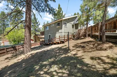a house in the woods with a fence and trees at Modern Lake Cabin for Family, Friends and Pets! in Big Bear Lake