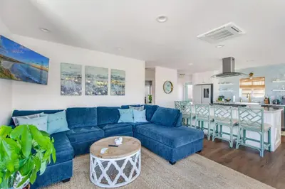 a living room with a blue couch and a kitchen at Luxury Ocean View Condo Steps To The Sand VIEWS in Manhattan Beach