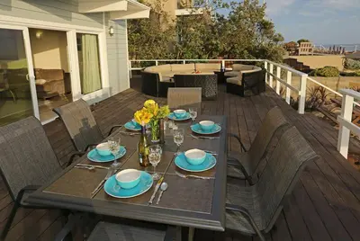 a wooden deck with a table and chairs on a patio at Seacliff Beach House by Paradise Retreats in Ventura