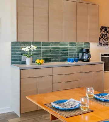 a kitchen with wooden cabinets and a table with plates at Seahorse Retreat by Paradise Retreats in Carpinteria