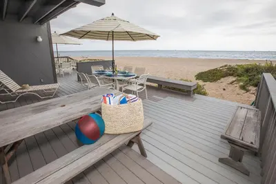 a deck with a picnic table and an umbrella on the beach at Seahorse Retreat by Paradise Retreats in Carpinteria