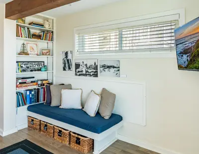a bench in a room with a window and bookshelves at Seahorse Retreat by Paradise Retreats in Carpinteria