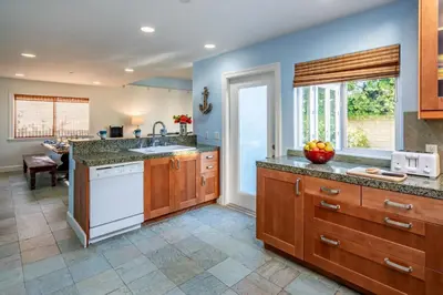 a large kitchen with wooden cabinets and a white dishwasher at Summer Sunset by Paradise Retreats in Ventura