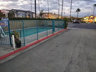 a fence with a swimming pool next to a street at Crzy 8 Motel in Orange