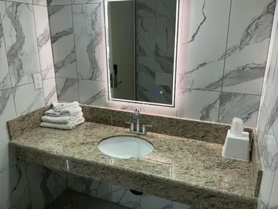 a bathroom with a sink and a mirror and towels at Crzy 8 Motel in Orange